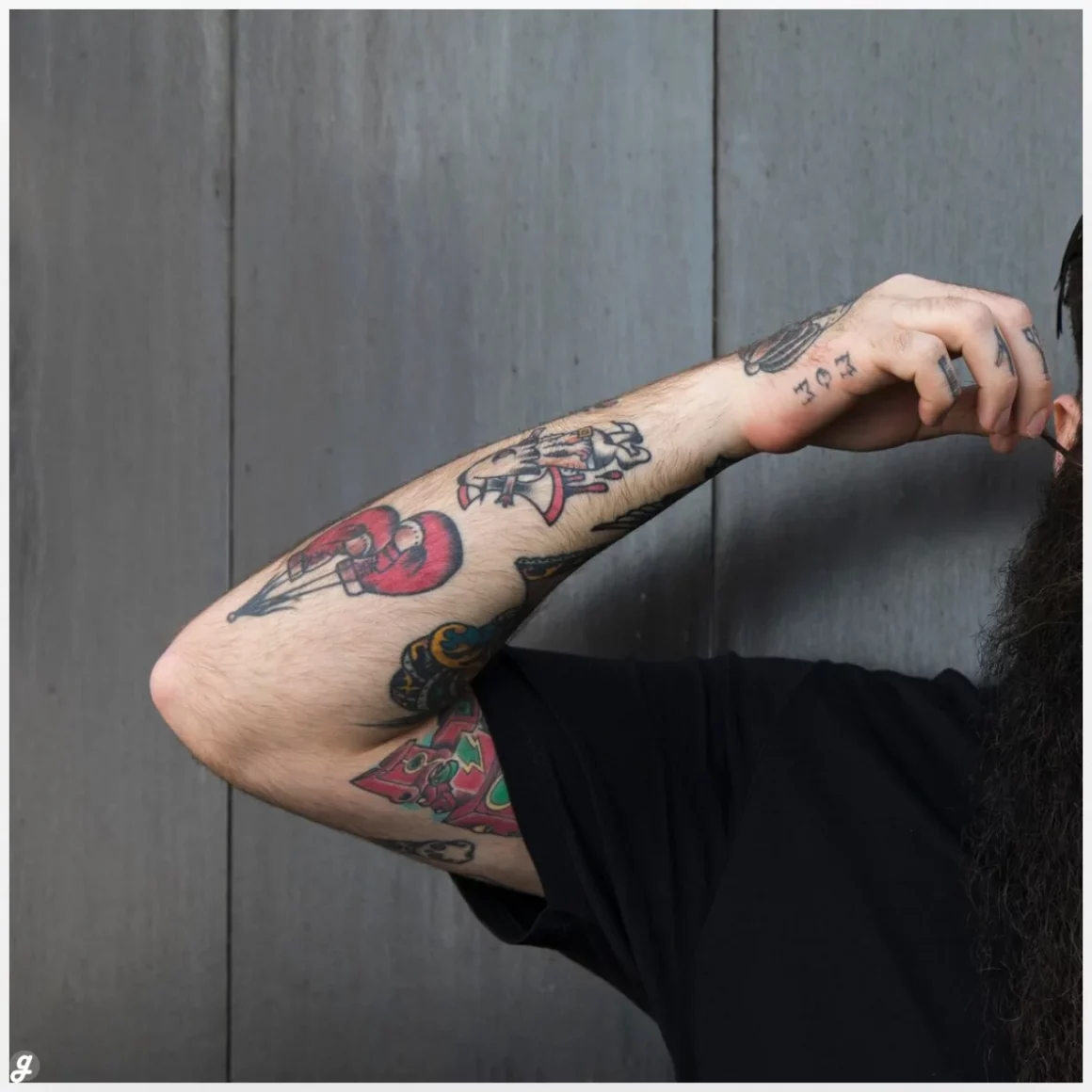 Close-up of a man with tattoo on his hand standing against grey wooden wall