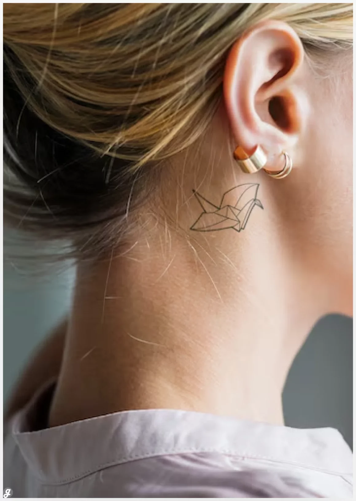 Closeup of a simple behind the ear tattoo of a young woman