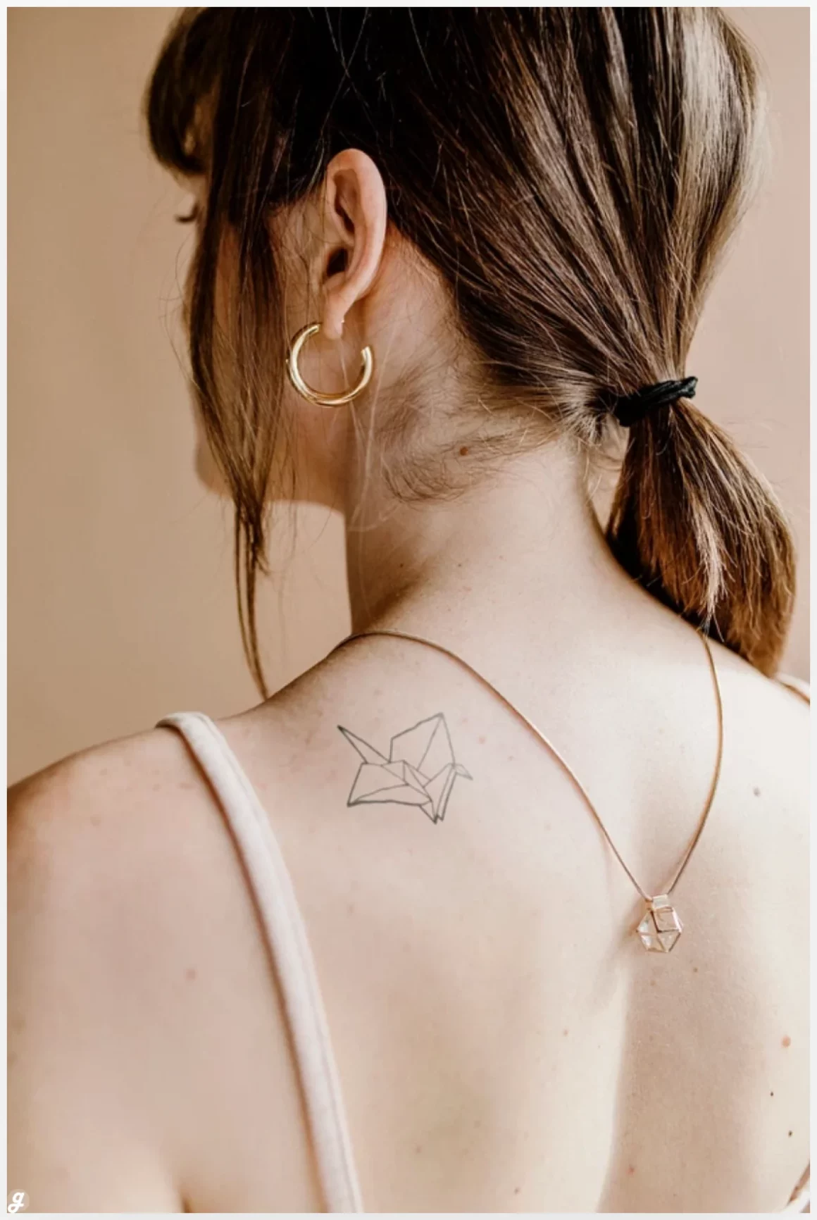 Woman with a paper bird tattoo on her shoulder